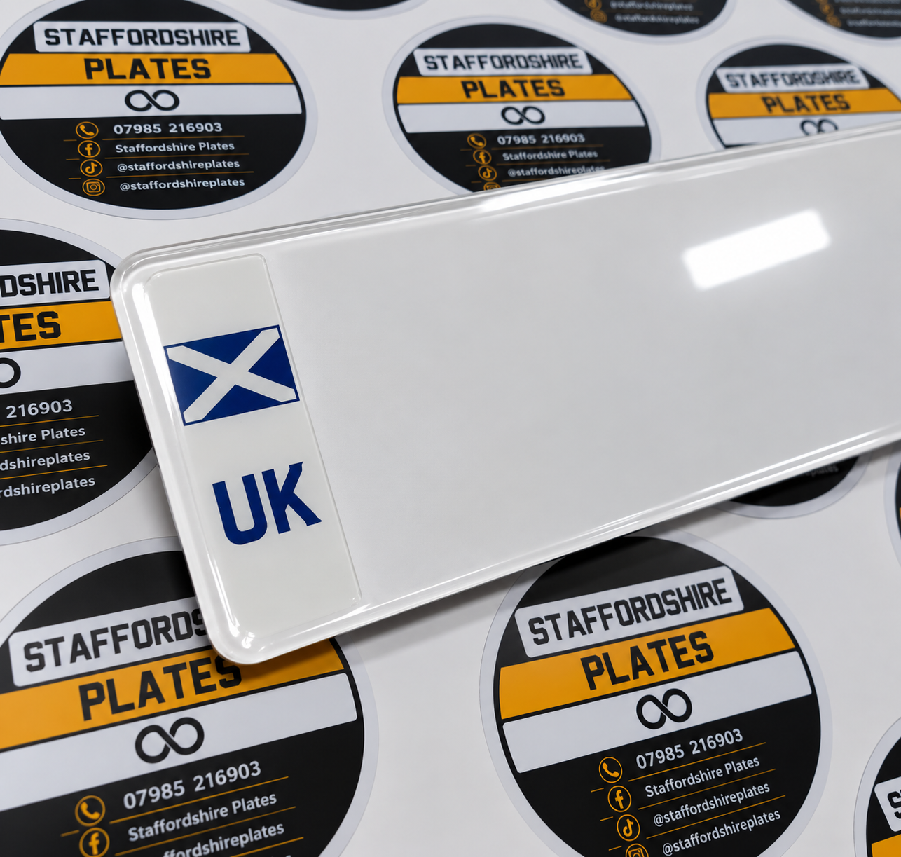 White number plate with a Scottish flag and UK badge